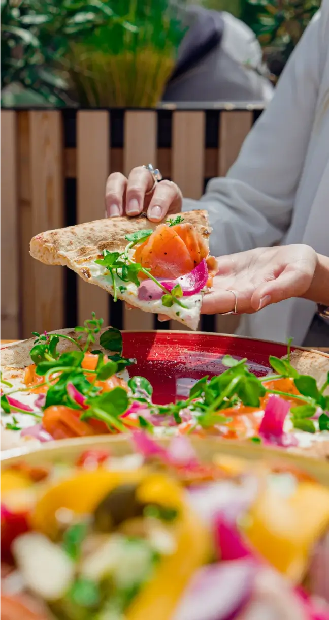 Personne tenant une part de pizza dans sa main